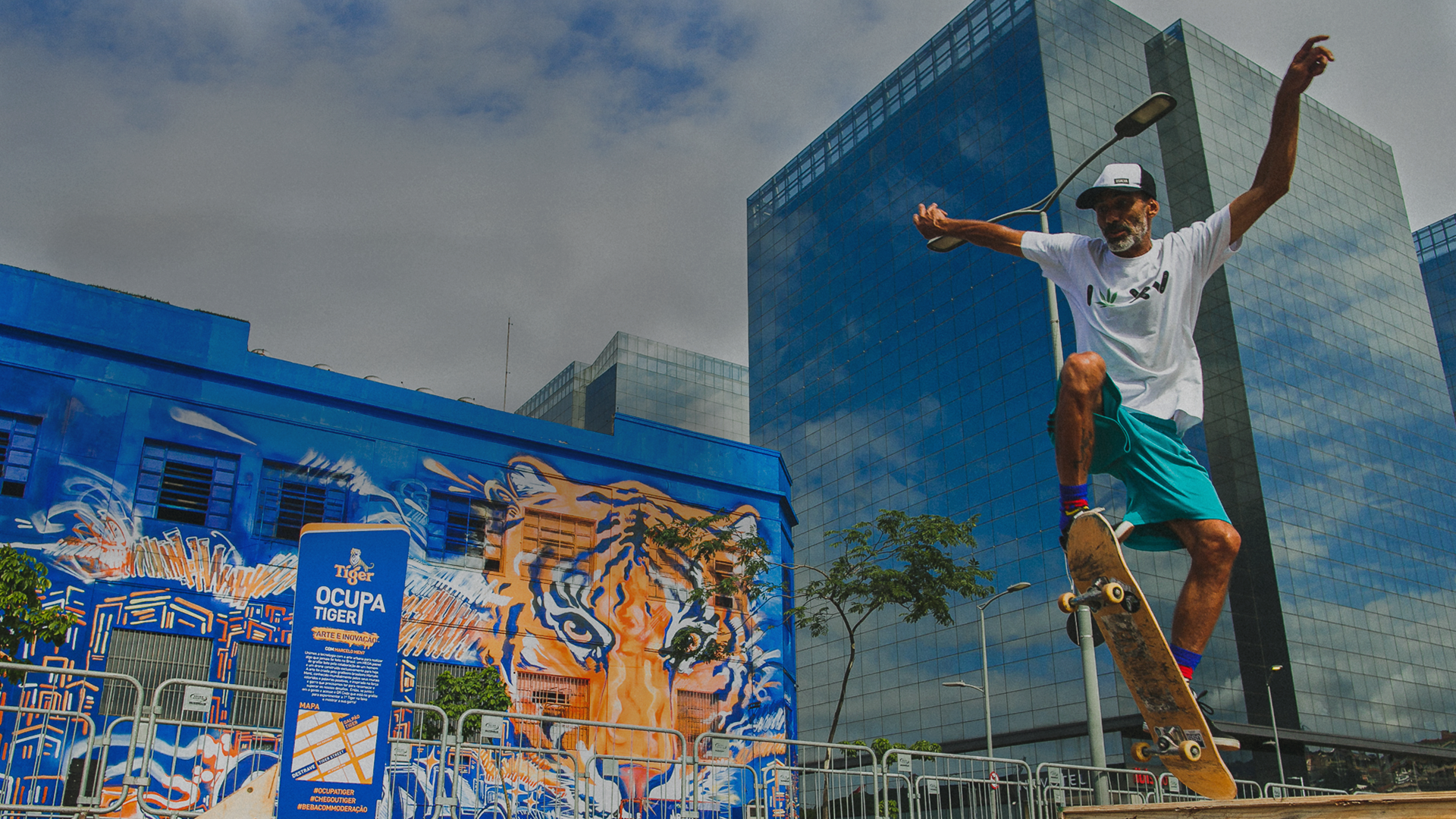 Manobra de skate na frente de um prédio com tigre grafitado.