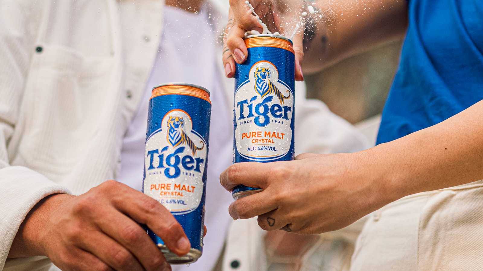 2 pessoas brindando e abrindo uma cerveja Tiger.